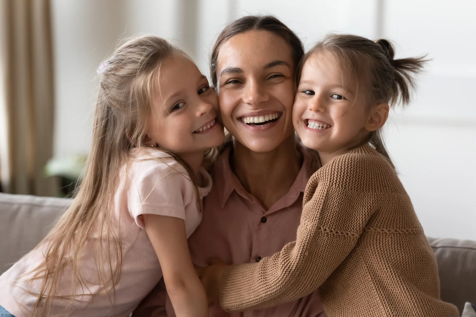 A mother smiling with her two daughters at home