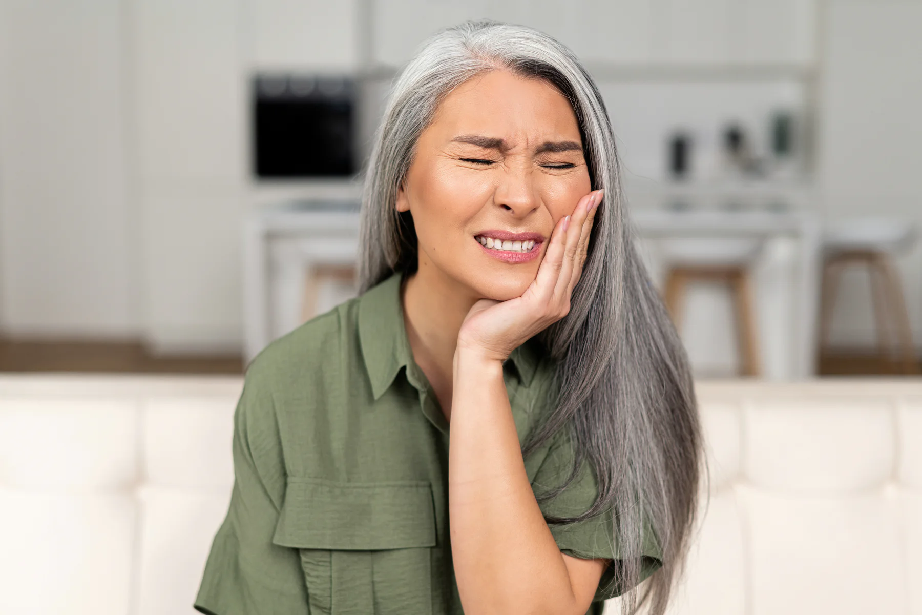A woman experiencing tooth pain at home