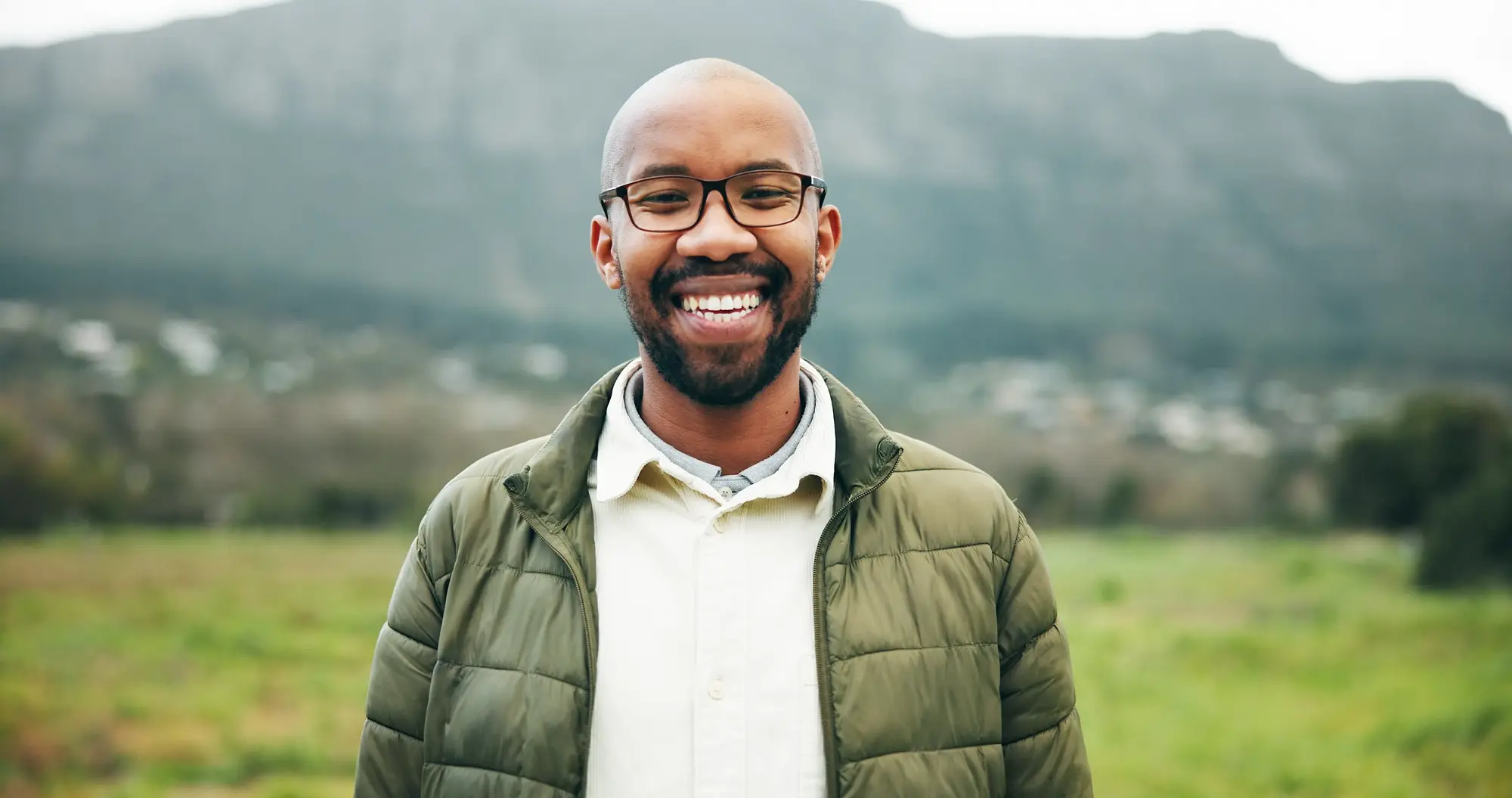 A smiling man outdoors with a mountain backdrop